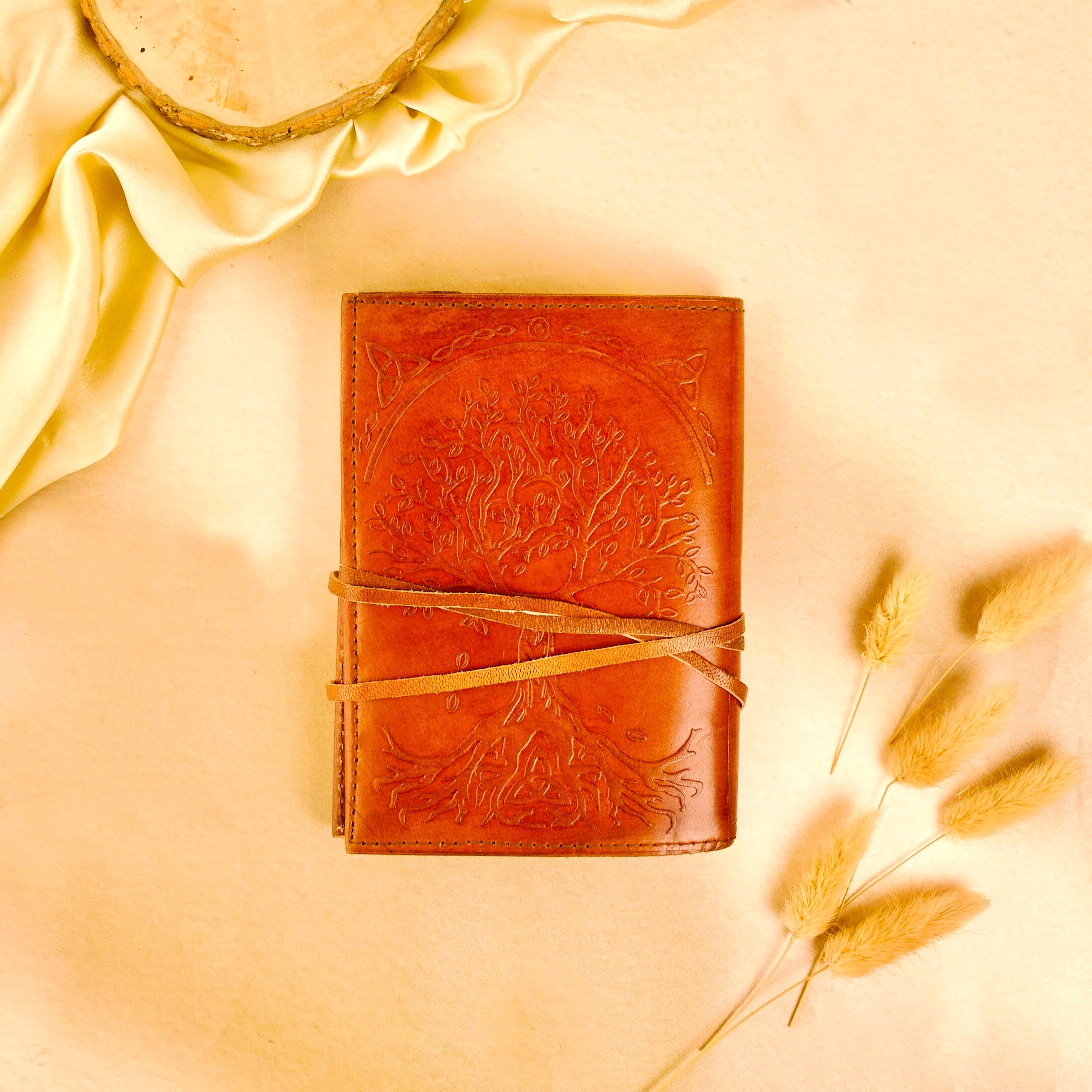 Brown leather journal with embossed design on a beige background